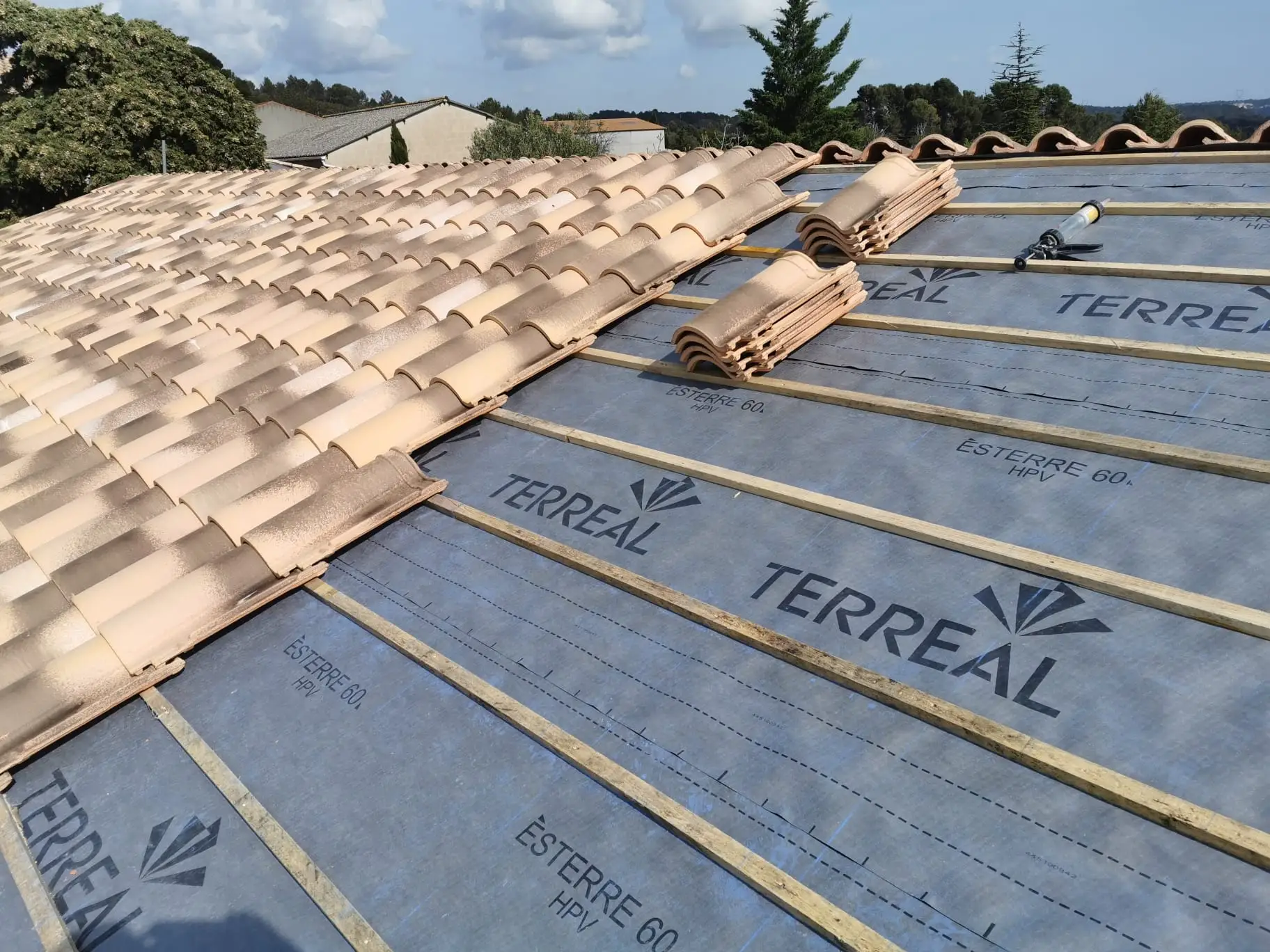 Rampant équipé d'un écran de sous-toiture et d'un liteaunage régulier, avec les paquets de tuiles neuves répartis sur la surface avant la pose
